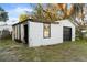 A view of a detached garage with a black door and small window set amongst trees and an expansive green yard at 126 Mason St, Auburndale, FL 33823