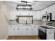 Modern kitchen featuring white cabinetry, stainless steel appliances, and stylish lighting fixture at 126 Mason St, Auburndale, FL 33823