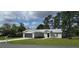 A single-story home featuring gray siding, black front door, a garage and manicured lawn at 13650 Sw 43Rd Cir, Ocala, FL 34473