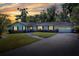 Exterior twilight view of a home, windows illuminated, showing the landscaped yard, and attached garage at 1655 John Arthur Way, Lakeland, FL 33803