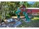 Backyard with a fun wooden playset with swings and slides, surrounded by mature trees at 1655 John Arthur Way, Lakeland, FL 33803