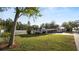 Lush front yard featuring a large shade tree and parked RV with a single-story home and a covered carport in the background at 2104 W End Ave, Lakeland, FL 33803