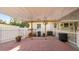 The covered patio features brick flooring, an overhead fan, string lights, and a white picket fence at 2104 W End Ave, Lakeland, FL 33803