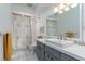 Bathroom with gray vanity, white tile flooring, shower with patterned curtain and white walls at 221 Stevenson Rd, Winter Haven, FL 33884