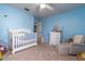 Light blue Bedroom featuring a crib, white dresser with mirror, chair with ottoman, and neutral carpet at 221 Stevenson Rd, Winter Haven, FL 33884