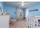 Bright Bedroom with soft blue walls, neutral carpet, white trim, ceiling fan, and white baby furniture at 221 Stevenson Rd, Winter Haven, FL 33884