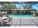 Enclosed swimming pool featuring light turquoise water, stone home accents, and an outdoor seating area at 2329 Duff Rd, Lakeland, FL 33810