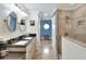 Bright bathroom showcasing a double sink vanity with a glass walk-in shower and a blue painted hallway at 2653 State Road 557, Lake Alfred, FL 33850