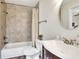 Cozy bathroom includes a shower and tub with tile surround, vanity, and matching rounded mirror at 2653 State Road 557, Lake Alfred, FL 33850