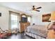 Charming bedroom boasts a ceiling fan, beautiful window view, and a decorative dresser with TV at 2653 State Road 557, Lake Alfred, FL 33850