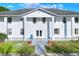 Well-maintained white home featuring manicured lawn, columns, and blue Adirondack chair on the front porch at 2653 State Road 557, Lake Alfred, FL 33850