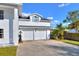 Two-car garage of a home, features white doors, a bell, and lush landscaping at 2653 State Road 557, Lake Alfred, FL 33850