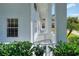 Side porch showcasing white railings, columns, and a view of lush greenery, with a blue chair at 2653 State Road 557, Lake Alfred, FL 33850