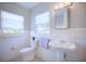 Bright, renovated bathroom showcases a pedestal sink, tiled walls, and window views at 2816 Fairmount Ave, Lakeland, FL 33803