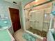 Bathroom featuring a glass-enclosed shower with decorative stones, vanity, and a wooden door at 302 Luna Rd, Auburndale, FL 33823