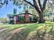 Charming brick home with a large tree and lush green lawn at 302 Luna Rd, Auburndale, FL 33823