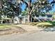 View of the house with mature landscaping and a car port at 302 Luna Rd, Auburndale, FL 33823