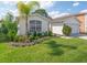 Beautifully landscaped front yard with lush green grass, a palm tree and colorful flowers at 307 Balmoral Ct, Davenport, FL 33896