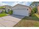 Exterior view of a white home featuring a two-car garage and well-maintained landscaping at 307 Balmoral Ct, Davenport, FL 33896