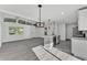 Bright living room featuring grey wood floors, modern lighting, and a view of the entry and kitchen at 3134 Hilltop S Ave, Lakeland, FL 33803