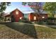 Red home exterior with a covered patio, lush landscaping, and a brick walkway, blending rustic charm and outdoor living at 3530 Hamilton Rd, Lakeland, FL 33811