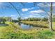 Backyard pond with lush green edges reflecting a blue sky with scattered clouds at 3530 Hamilton Rd, Lakeland, FL 33811