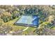 Aerial view of a fenced tennis court nestled in a wooded area with green surroundings and walkway at 4232 Prima Lago Dr, Lakeland, FL 33810