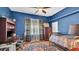 This blue bedroom includes a desk, a bed with plaid blankets, and windows with natural light at 5638 Bloomfield Blvd, Lakeland, FL 33810