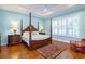 Bedroom with light-blue walls, wood floors, four-poster bed, and window shutters at 5789 Lake Victoria Dr, Lakeland, FL 33813