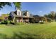 Charming two-story home with a well-manicured lawn, lush landscaping, and welcoming front porch on a sunny day at 5789 Lake Victoria Dr, Lakeland, FL 33813