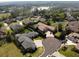 Aerial view of multiple homes in a verdant neighborhood with mature trees and a lake in the distance at 6470 Ashley Dr, Lakeland, FL 33813