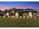 Charming home featuring a manicured lawn, lush landscaping, and inviting front entrance at dusk at 6720 Highlands Creek Loop, Lakeland, FL 33813