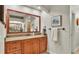 Vanity with granite countertop, wood cabinets, framed mirror and decorative wall art in a well-lit bathroom at 6774 Crescent Woods Cir, Lakeland, FL 33813