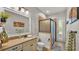 Bright bathroom featuring a vanity with solid countertops, a framed mirror, and a glass-enclosed shower at 6774 Crescent Woods Cir, Lakeland, FL 33813
