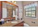 Well-lit bathroom featuring a granite countertop vanity, a framed mirror, and a shower with tile surround at 6774 Crescent Woods Cir, Lakeland, FL 33813