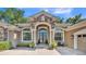 Home's elegant front entrance features stone accents, columns, and decorative shrubbery at 6774 Crescent Woods Cir, Lakeland, FL 33813