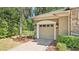 Attached garage with a neutral door, landscaping, and an adjacent brick paver driveway at 6774 Crescent Woods Cir, Lakeland, FL 33813