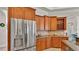 Kitchen area featuring stainless steel refrigerator, wooden cabinetry, and granite counters at 6774 Crescent Woods Cir, Lakeland, FL 33813