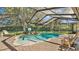 Inviting screened-in pool area with brick pavers, a waterfall feature, and comfortable lounge seating at 6774 Crescent Woods Cir, Lakeland, FL 33813