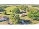 Aerial view of a home with a large grassy yard, outbuildings, and surrounding greenery at 6981 Snell Rd, Bartow, FL 33830
