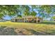 Single-story home with stucco exterior, complemented by green lawn and mature trees with a detached shed in the background at 6981 Snell Rd, Bartow, FL 33830