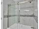 Modern bathroom shower featuring sliding glass doors and elegant marble-look tile and accent trim at 6981 Snell Rd, Bartow, FL 33830