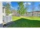 Spacious, grassy backyard with mature landscaping and privacy fence and the home's AC unit at 7445 Ibis Dr, Lakeland, FL 33810