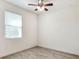 A bright, empty bedroom featuring a ceiling fan, window with blinds, and light, neutral-toned walls and flooring at 7445 Ibis Dr, Lakeland, FL 33810