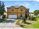 Two-story home featuring a two-car garage, and a well-manicured lawn with vibrant landscaping at 181 James Cir, Lake Alfred, FL 33850