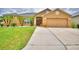 Inviting tan home showcasing a well-maintained lawn, a two-car garage, and a welcoming front entrance at 4069 Byrds Crossing Dr, Lakeland, FL 33812