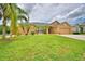 Beautiful single Gathering home with a well manicured green lawn, palm trees, and tan exterior paint at 4069 Byrds Crossing Dr, Lakeland, FL 33812