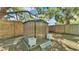 Durable metal storage shed on a wooden platform, enclosed by a wooden fence, with flower pots near the entrance at 605 Forrest Dr, Bartow, FL 33830