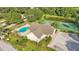 Aerial view of a community pool, tennis court and clubhouse with lush green landscaping and mature trees at 6775 Lake Clark Dr, Lakeland, FL 33813