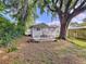 Quaint backyard with patio, large tree providing shade, and lush foliage throughout the property at 923 Lexington St, Lakeland, FL 33801